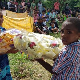 Two children waiting to place their floral tributes on the top of the grave